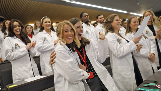 Happy students in white coats celebrating