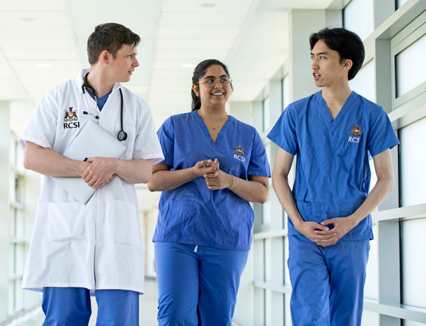 Three medical professionals walk along a corridor
