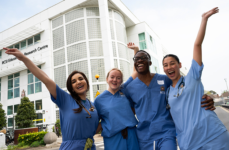 Four RCSI Medical students in scrubs celebrate the end of their exams outside the ERC in Beaumont Hospital.