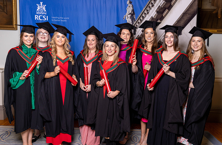 A large group of graduates pose in their conferring gowns and mortarboards. 