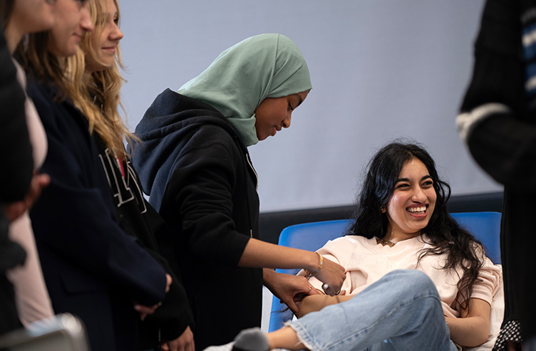 Students smile as they practice their clinicsl skills on each other.