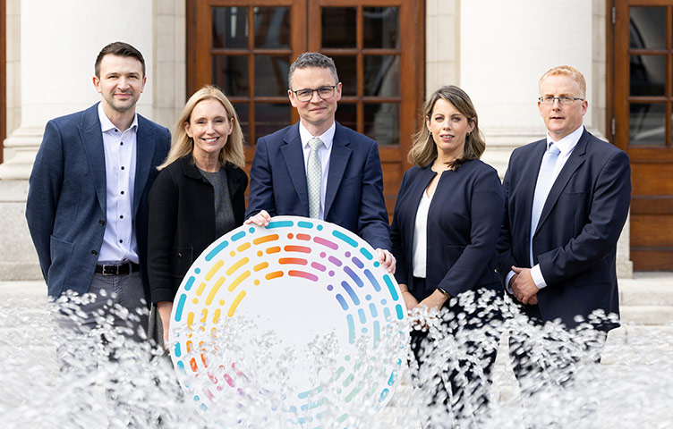 Pictured outside Government buildings behind a fountain are five people (L-R) Dr Damir Vareslija, Professor Leonie Young, Minister for Further and Higher Education, Research Innovation and Science Patrick O’Donovan TD; Claire Noonan; and Seamus Browne.