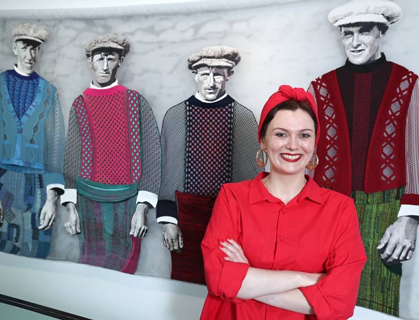 Art award winner poses in front of winning artwork