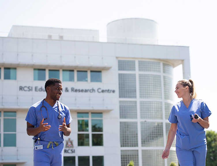 Two doctors talking and laughing in front of RCSI Education and Research Centre