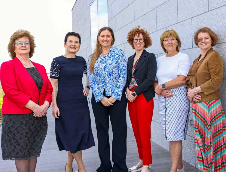 A group pose for a photo in a row outdoors