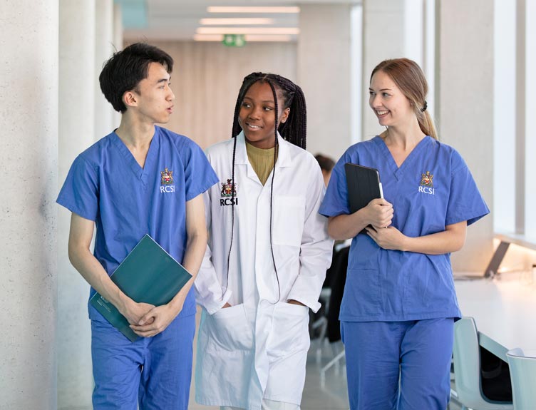 Three surgical students converse in university corridor