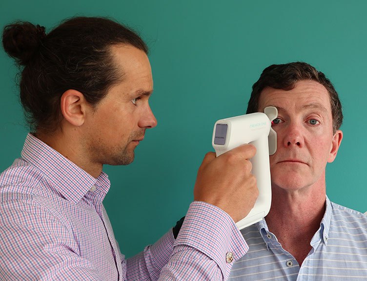 Head Diagnostics A technician uses an iTremor One device to measure a test subject's ocular microtremors.