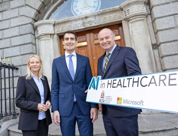 Three people pictured in front of historic building at AI in Healthcare launch