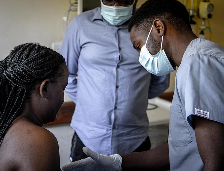 A doctor examines a woman's breasts as part of the Akazi project in Malawi