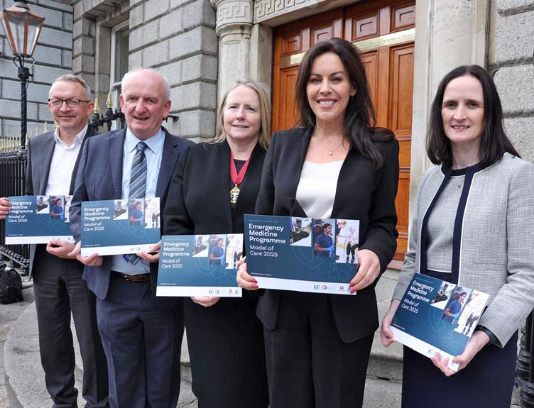 Emergency Medicine Programme Model of Care Five people in front of old building hold brochures