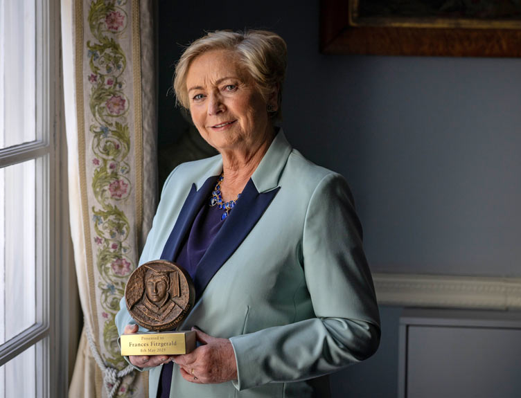 Frances Fitzgerald Awardee holding trophy by a window