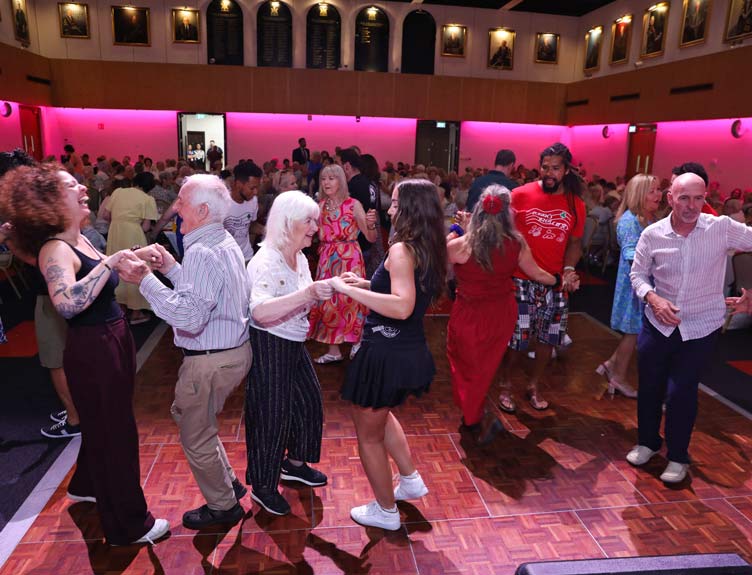 People of different ages dancing together on a wooden dance floor in exam hall at RCSI.