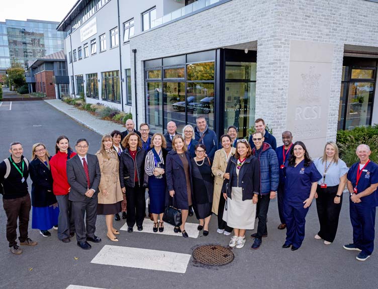 Group photo of staff and visitors standing outside the RCSI School of Dentistry building entrance.