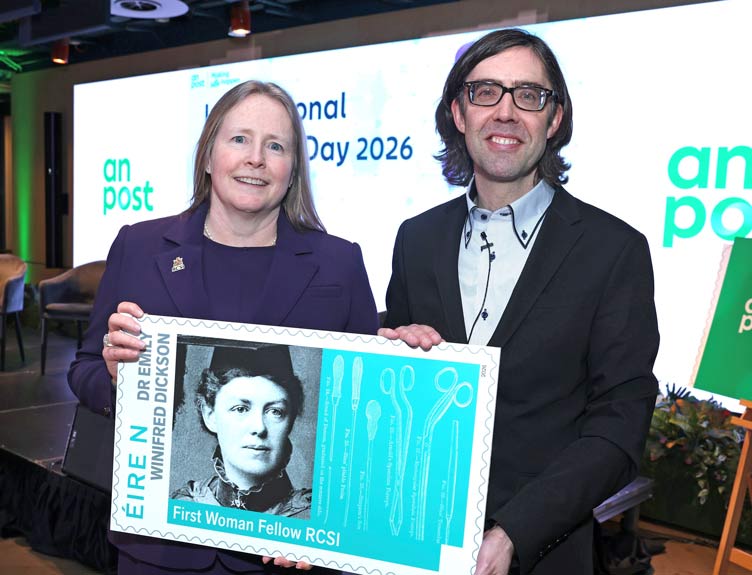 An oversized print of the Emily Winifred Dickson stamp design is help by two individuals