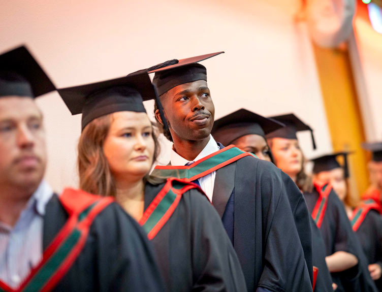 Conferees wearing mortarboards and gowns at ceremony