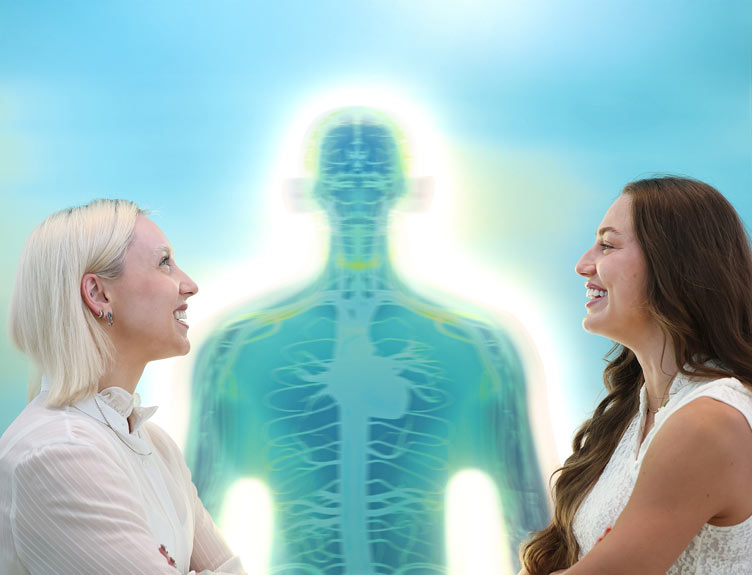 Athletes Orla Comerford and Sophie Becker face each other in profile with a glowing translucent human body illustration showing internal anatomy between them against a blue background.