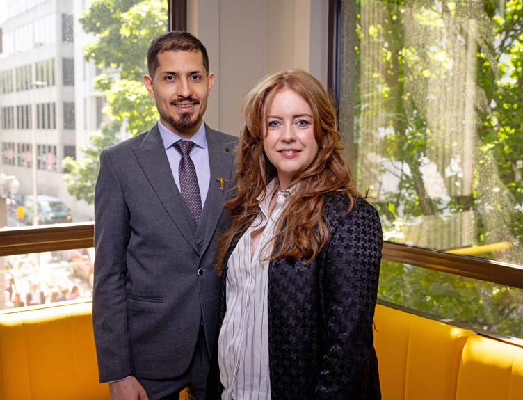  Doctors Sina Javadpour and Claire Conway stand in front of window overlooking tree-lined street