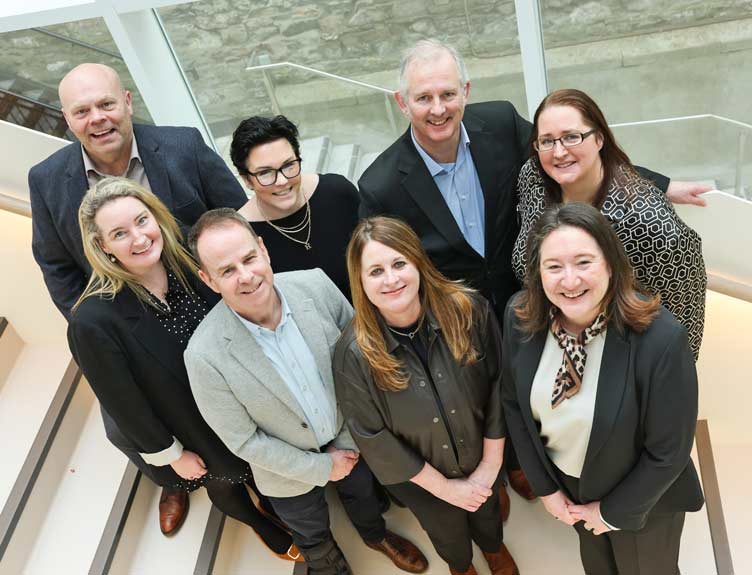 Large group of the Faculty's medical professionals on staircase photographed from above.
