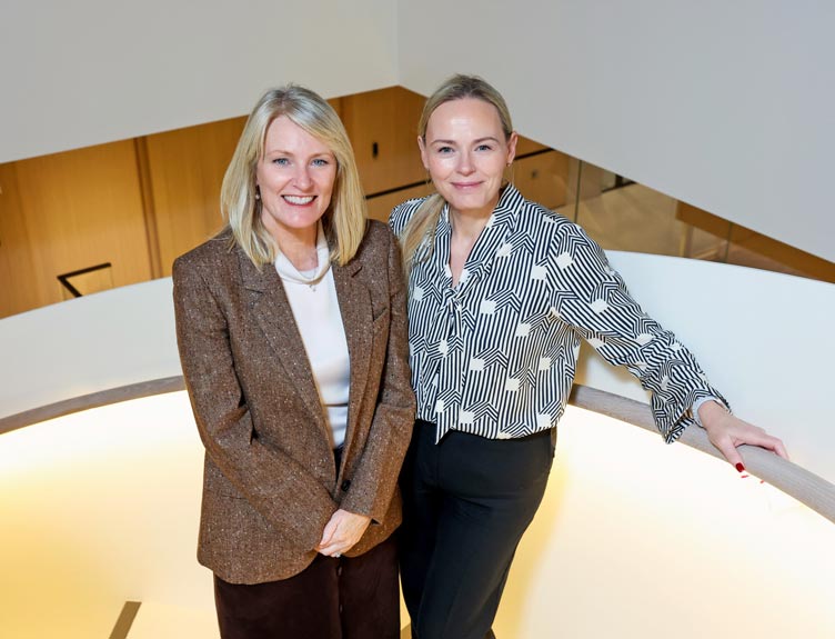 Two people smiling while pictured on a spiral staircase