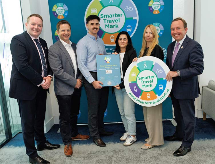 RCSI’s Estates team posing with a Smarter Travel Mark certificate and promotional sign in front of a branded display celebrating sustainable travel initiatives.