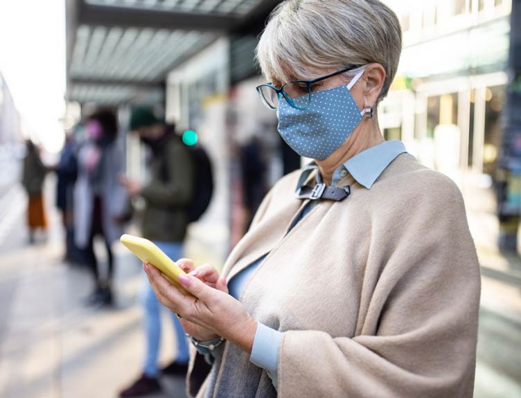 Lady wearing a mask at a train station
