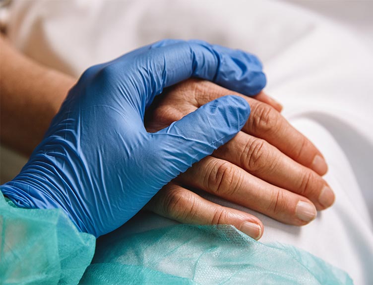Medical staff's hand in glove on patient's hand