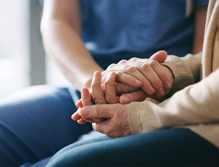 Healthcare worker and patient holding hands 