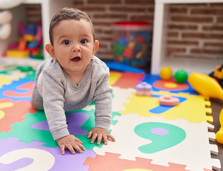 A baby crawling on the floor at a creche