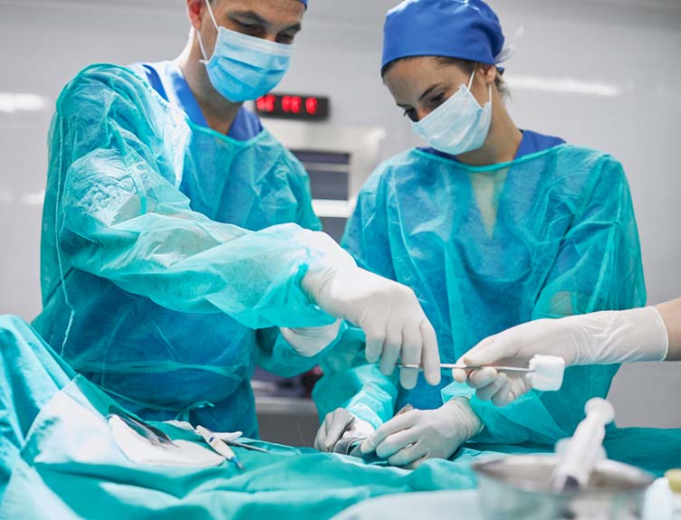 Two surgeons wearing full PPE in operating theatre performing surgery.