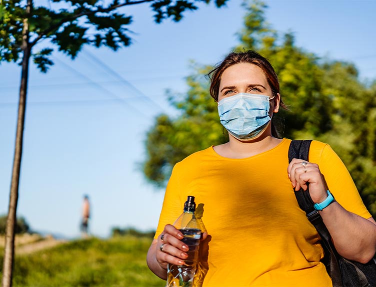 Woman walking with mask and water