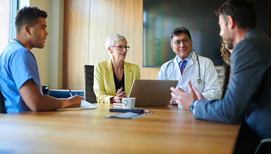 Healthcare professionals seated around a table during a multidisciplinary team discussion.