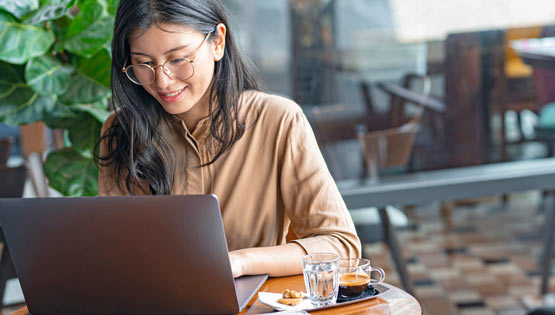 A woman studies on a laptop with a coffee