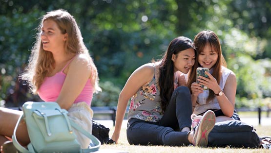 Students relax in a park in the sunshine