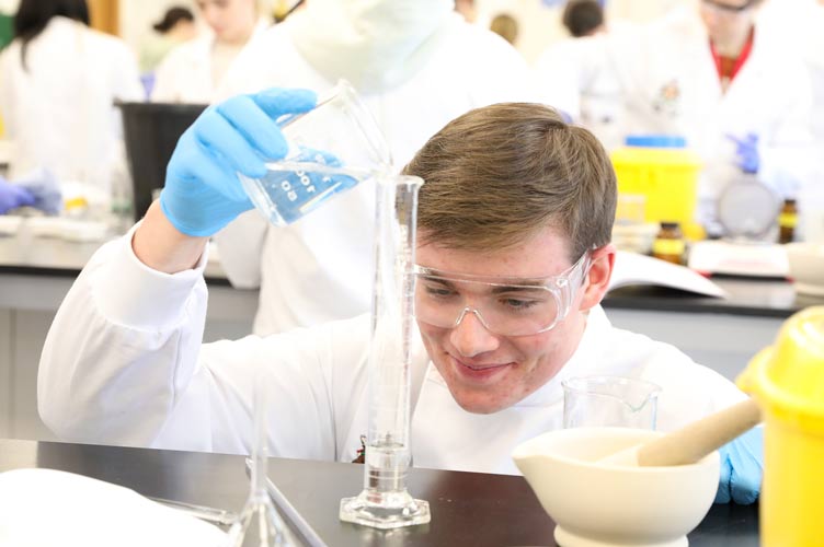 Student wearing white coat in lab setting