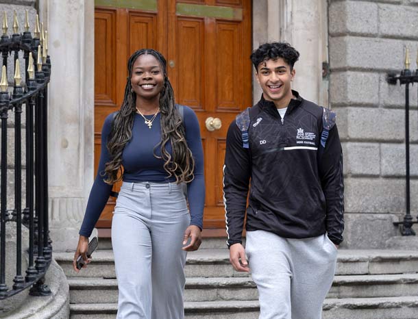 Happy students walk together outside old university building
