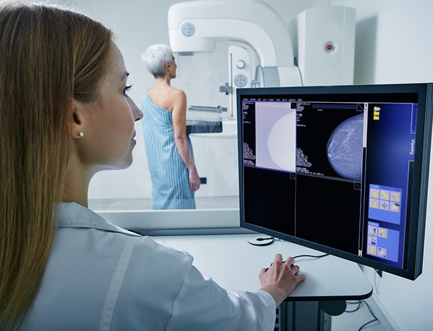 Medical technician taking mammogram exam of female patient.