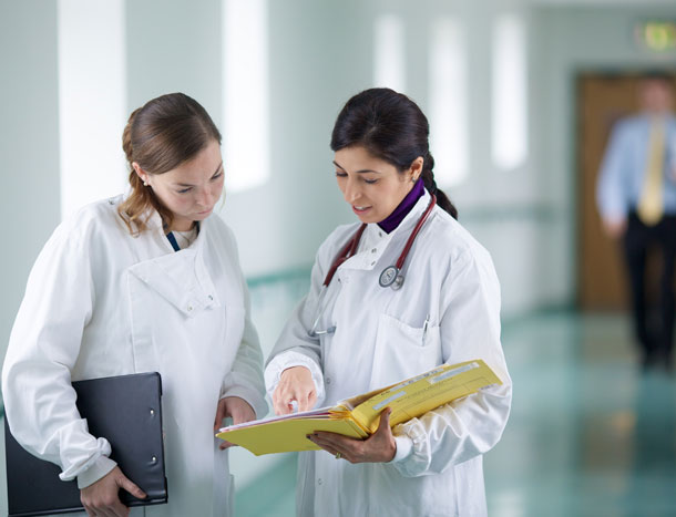 Doctors discussing case file in hallway