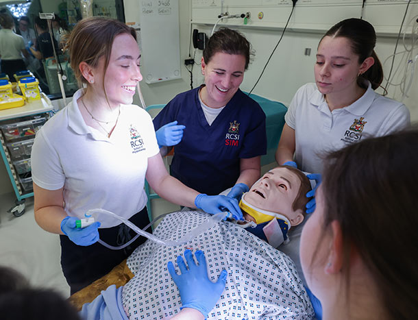 Healthcare students gathered around a patient simulator during a clinical skills session, practising airway management and patient assessment in a simulation laboratory.