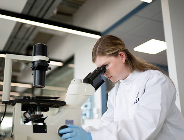 RCSI researchers in a white coat using a microscope
