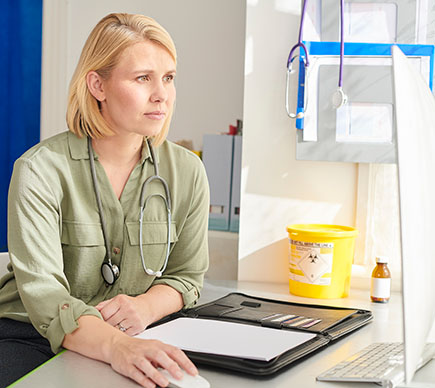 A doctor using a desktop computer in her clinic.