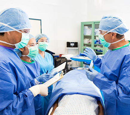 Surgeon teaching hospital interns during operating on patient