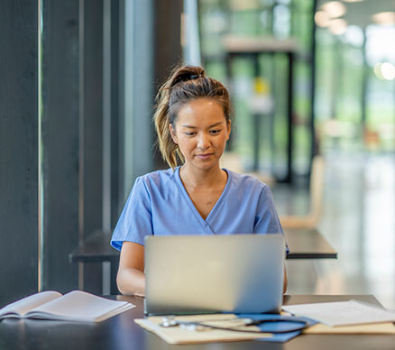 A medical professional working at a laptop.