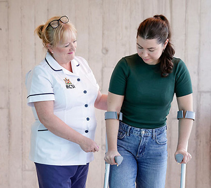 A nurse assists a patient who is using crutches.