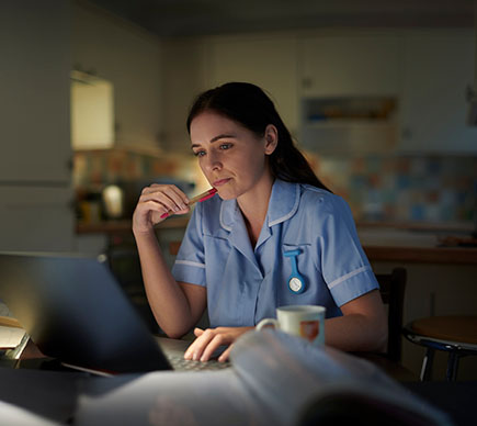 A female nurse working at a laptop computer.
