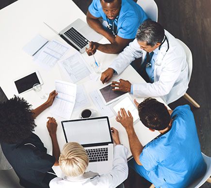 A group of medical professionals sitting at a desk, photographed from above.