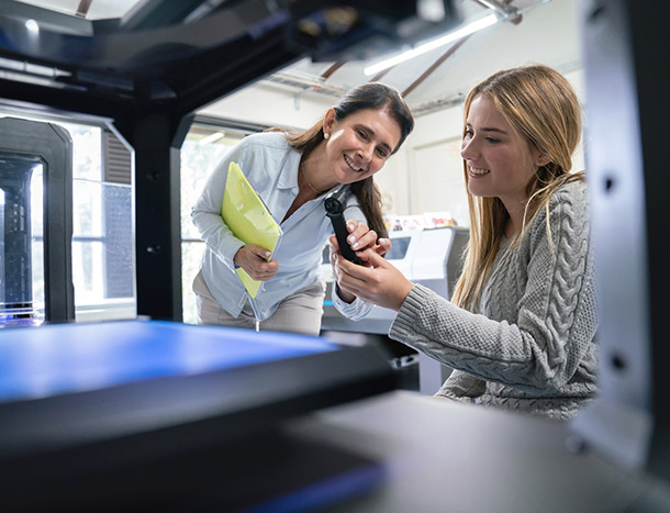Two professionals collaborate beside advanced laboratory equipment, examining a sample and discussing results in a modern research setting.