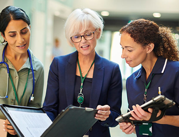 Three medical professionals conferring in a hospital corridor.
