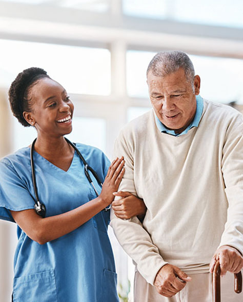 A female nurse assisting an elderly man who is using a walking aid.