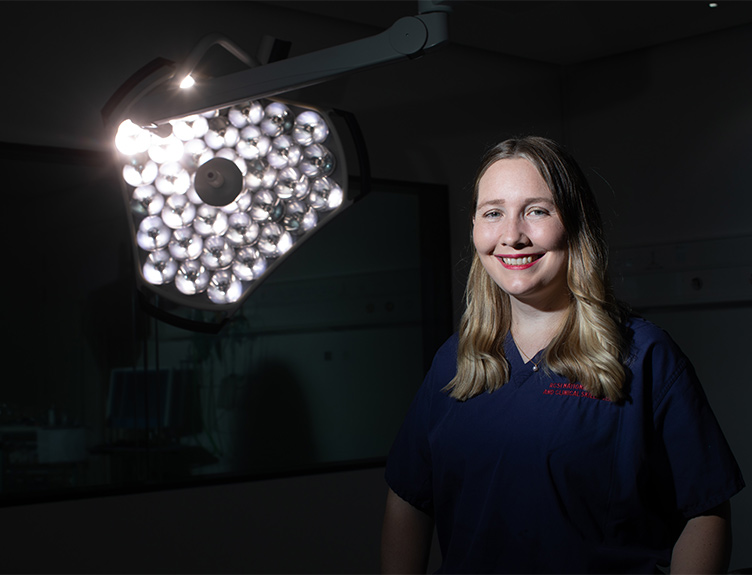 Dr Evelyn Murphy standing in a darkened operating theatre with surgical lights on