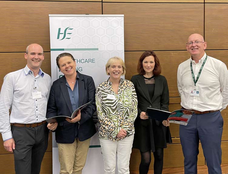 Five people stand in front of a HSE banner